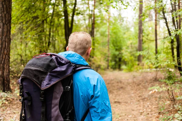 Wanderer mit Rucksack ist im Herbstwald unterwegs. — Stockfoto