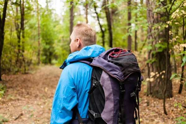 Wanderer mit Rucksack ist im Herbstwald unterwegs. — Stockfoto