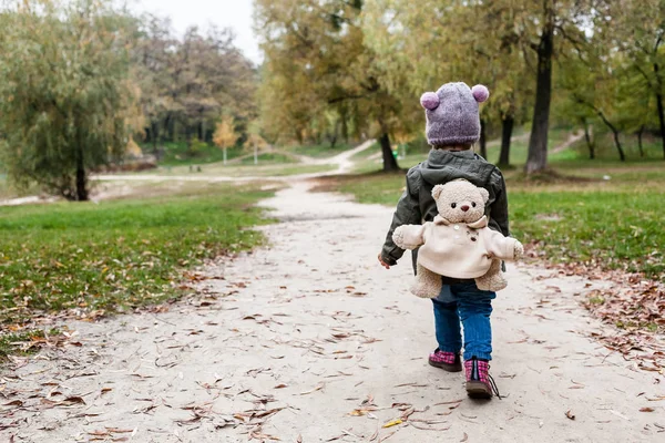 Niña en el bosque de otoño con mochila de oso de peluche . —  Fotos de Stock