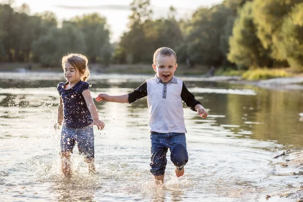 Duas crianças felizes correndo pela água no verão — Fotografia de Stock