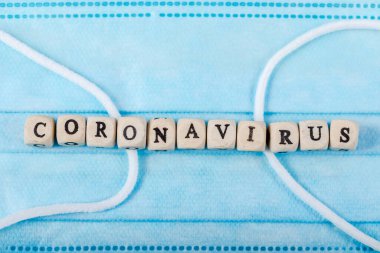 Coronavirus kelimesi tahta blokta yazılı. Coronavirus metninin maske üzerindeki hali nedir? Coronavirus kavramının üst görünümü için.