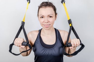 Üst beden egzersizi konsepti. Stüdyoda askılarla egzersiz yapan güzel bir kadın resmi. TRX kavramı beyaz arkaplanda izole edildi.
