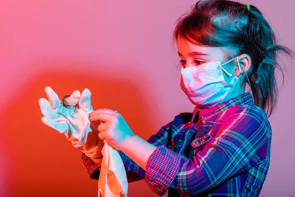 小さな女の子は 安全性 病気や大気汚染のための彼女の鼻の上にマスクとコロナウイルスCovid 子供から身を守るファブリックマスクを持っています 異なる色の光で撮影したスタジオ — ストック写真