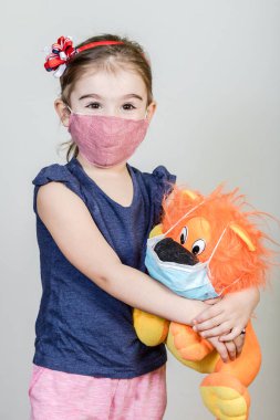 Küçük kızın kumaş maskesi var. Kendini Coronavirus COVID-19 'dan koruyor. Maskeli bir çocuk..
