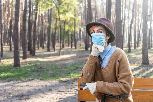 コロナウイルスから身を守るためにマスクと手袋をしたスタイリッシュな女性 都市や公園内の電動スクーターを使用して安全になるために — ストック写真