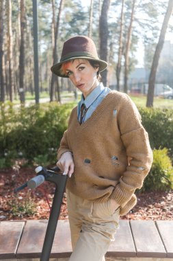 Koronavirüsten kurtulmak için maske ve eldiven takmayan şık bir kadın. Şehirde elektrikli scooter kullanıp güvenli bir yere park etmek..