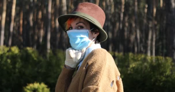 コロナウイルスから身を守るためにマスクと手袋をしたスタイリッシュな女性 都市や公園内の電動スクーターを使用して安全になるために — ストック動画