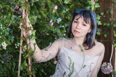 Güzel genç bir kadın bahar süslemeli stüdyoda çiçeklerle eğleniyor..