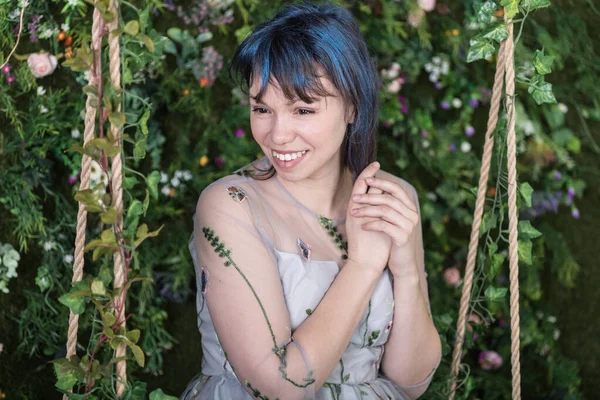 Güzel genç bir kadın bahar süslemeli stüdyoda çiçeklerle eğleniyor..