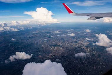 Kırmızı kanatlı mezun oldu. Koyu mavi gökyüzü. Aşağıdaki büyük şehrin güneş ışığı manzaralı.