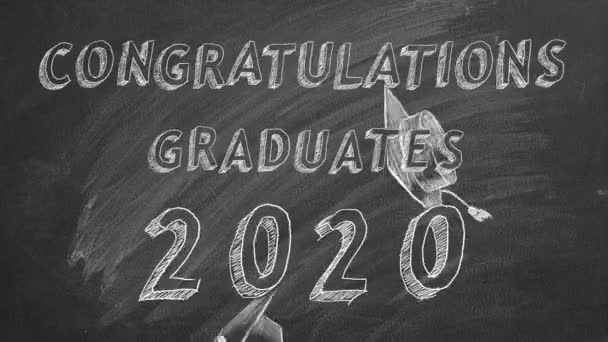 Rukopis Blahopřejeme absolventům. 2020.  a maturitní čepice na tabuli.