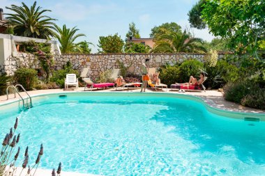 Yüzme havuzunun yanında güneşlenen üç beyaz adam.