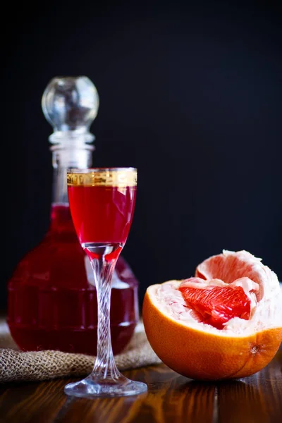Sweet grapefruit alcoholic cordial in the decanter with a glass — Stock Photo, Image