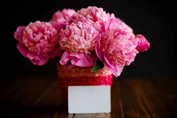 Boeket van roze pioenrozen in een rieten vaas — Stockfoto