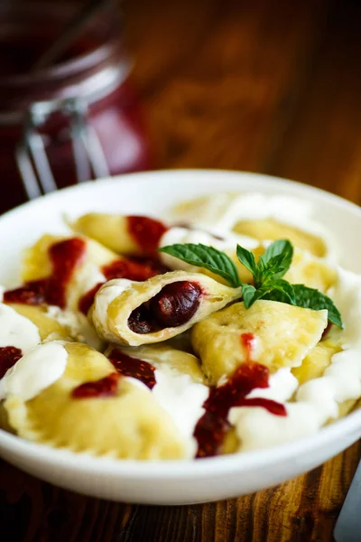 Homemade sweet dumplings with berries and sour cream
