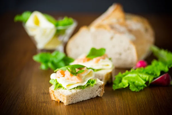 Sandwich mit Käse, Salatblättern und rotem Fisch auf einem Holztisch — Stockfoto