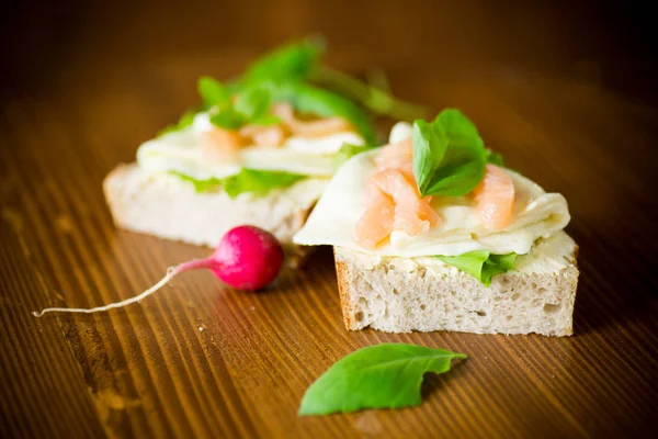 Sanduíche com queijo, folhas de salada e peixe vermelho em uma madeira — Fotografia de Stock