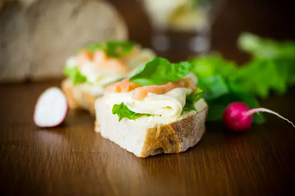 Sándwich con queso, hojas de ensalada y pescado rojo sobre una madera —  Fotos de Stock