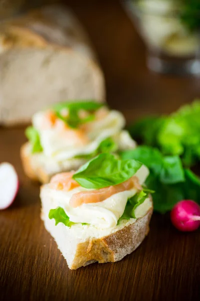 Σάντουιτς με τυρί, φύλλα σαλάτας και κόκκινα ψάρια σε ξύλινο — Φωτογραφία Αρχείου