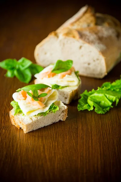 Sandwich au fromage, feuilles de salade et poisson rouge sur bois — Photo