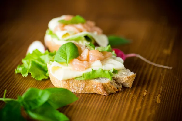 Sanduíche com queijo, folhas de salada e peixe vermelho em uma madeira — Fotografia de Stock