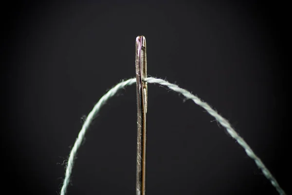 Thread stuck in a needle close-up on a black — Stock Photo, Image