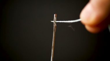 thread stuck in a needle close-up on a black background