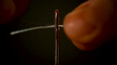 thread stuck in a needle close-up on a black background