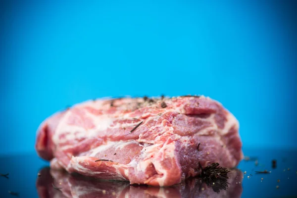 Surowe mięso wieprzowe z przyprawami i rozmarynem na niebiesko — Zdjęcie stockowe