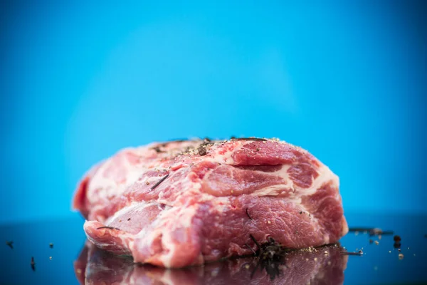 Trozo de carne de cerdo carne cruda con especias y romero en un azul —  Fotos de Stock