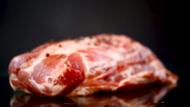 Свинячий шматок сирого м'яса зі спеціями та розмарином на темряві — стокове відео