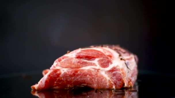 Trozo de carne de cerdo carne cruda con especias y romero en una oscuridad — Vídeo de stock