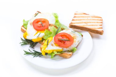 Yumurtalı kızarmış ekmek, marul, beyaz arka planda bir tabak domates.