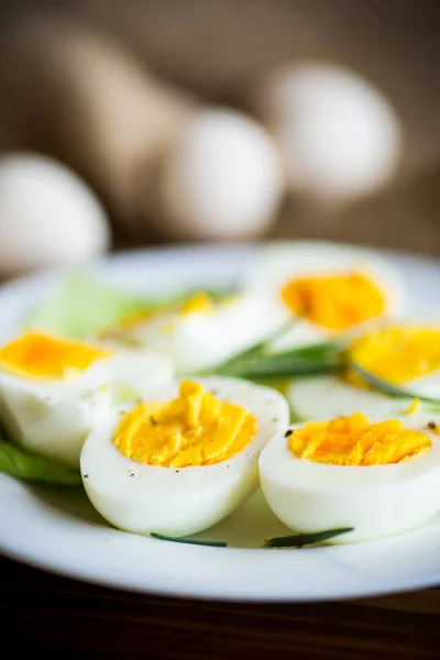boiled eggs with salad leaves in a plate on a wooden table