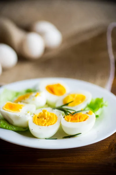 boiled eggs with salad leaves in a plate on a wooden table