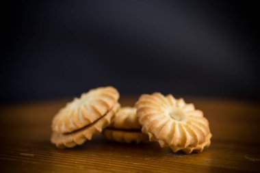 Tahta bir masanın üzerinde yoğunlaştırılmış sütle birlikte çıtır çıtır kurabiyeler.