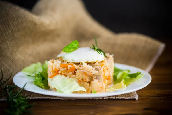 野菜と目玉焼きサラダの葉を木のテーブルの上の皿に盛ったご飯 — ストック写真