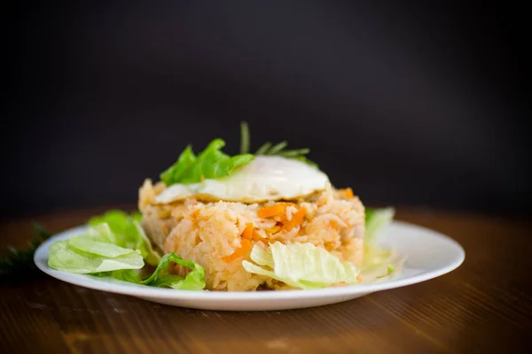 野菜と目玉焼きサラダの葉を木のテーブルの上の皿に盛ったご飯 — ストック写真