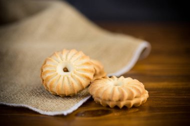 Tahta bir masanın üzerinde yoğunlaştırılmış sütle birlikte çıtır çıtır kurabiyeler.