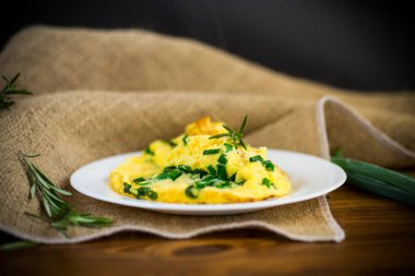 Tahta bir tabakta doğranmış yeşil soğanlı kızarmış omlet.