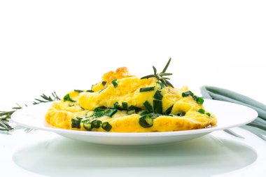 Beyaz arka planda izole edilmiş bir tabakta doğranmış yeşil soğanlı sıcak omlet.