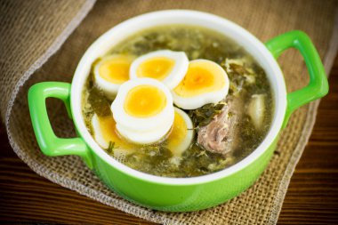 Yeşil doru taze bahar organik çorbası ve ahşap masada bir tabakta yumurta.