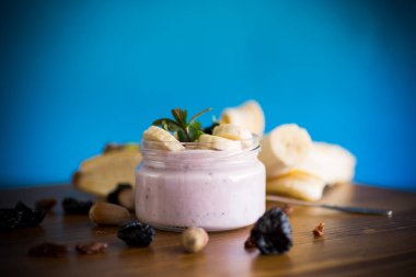 Muzlu tatlı yoğurt, kuru erik, cam kavanozdaki kuru üzümler ahşap bir masada.