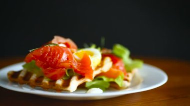 Salata yapraklı kızarmış ekmek ve ahşap bir masada tuzlanmış kırmızı balık.