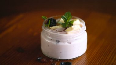 Muzlu tatlı yoğurt, kuru erik, cam kavanozdaki kuru üzümler ahşap bir masada.