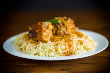 Ahşap bir masada et ve sos ile kaynatılmış vermicelli.