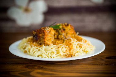 Ahşap bir masada et ve sos ile kaynatılmış vermicelli.