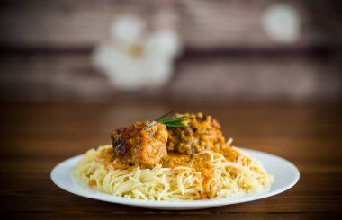 Ahşap bir masada et ve sos ile kaynatılmış vermicelli.