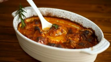 Baharatlı et ve sebze ve sos seramik formda, ahşap bir masada.