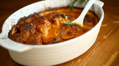 Baharatlı et ve sebze ve sos seramik formda, ahşap bir masada.